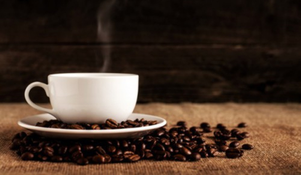 Photo of a white ceramic mug and saucer with coffee beans on brown textile by Mike Kenneally on Unsplash